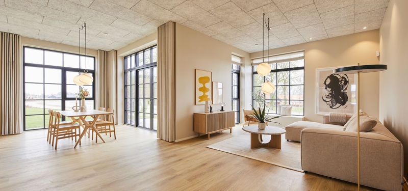 Lyst opholdsrum i moderne vinkelhus med spiseplads, beige sofa, store gulv-til-loft-vinduer og lange gardiner – inspiration til indretning og nye husdrømme.