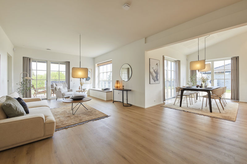 Stue og køkken-alrum fra eurodan-huse med stort sansevindue, brede vinduespartier mod haven, lys sofa, spiseplads og åben forbindelse mellem opholdsrum – konkret inspiration til nybyggeri, husbyggeri og moderne husdrømme.