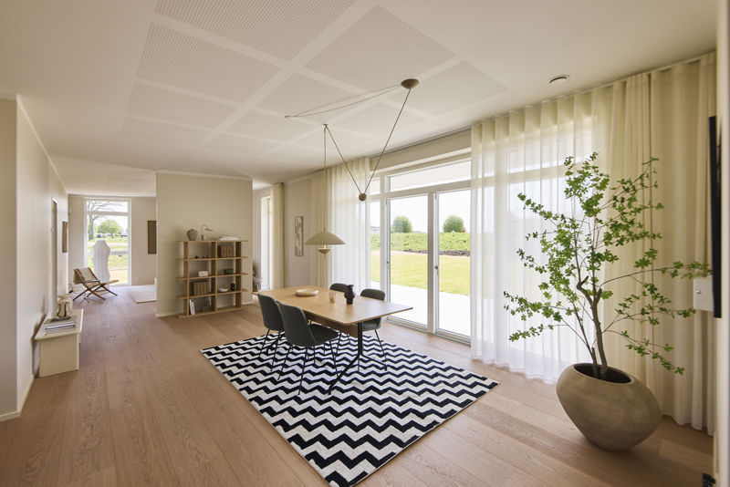 Lys spisestue i moderne hus med ensidig taghældning, spisebord, pendellamper og store glaspartier, der lukker dagslyset ind i hjemmet.