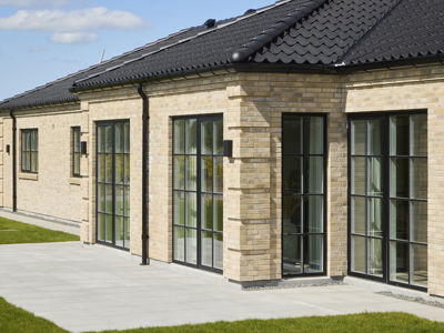 Murstenshus fra eurodan-huse med sort tegltag, store sprossede vinduespartier og flisebelagt terrasse, der giver inspiration til klassisk nybyggeri med moderne detaljer.
