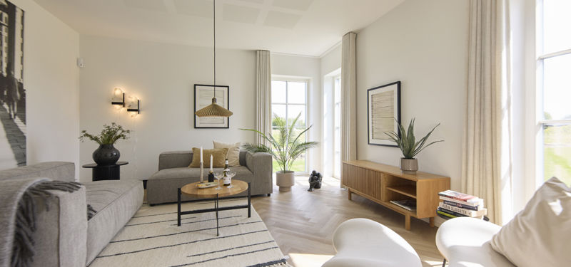 Lys og rummelig stue i udstillingshus fra eurodan-huse med store vinduer, sildebensgulv, sofaområde og moderne indretning, der giver inspiration til nybyggeri, husbyggeri og hyggelige opholdsrum i et nyt familiehus.
