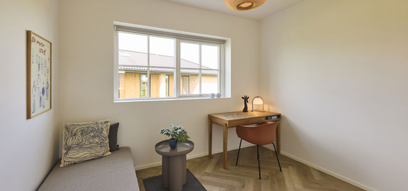 Lyst værelse i udstillingshus fra eurodan-huse med skrivebord, daybed, stort vindue og sildebensgulv, der giver inspiration til kontor, gæsteværelse og fleksible rum i moderne nybyggeri og husbyggeri.