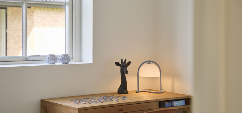 Lyst kontor i udstillingshus fra eurodan-huse med skrivebord, lampe og vindue, der giver inspiration til hjemmearbejdsplads i moderne nybyggeri.