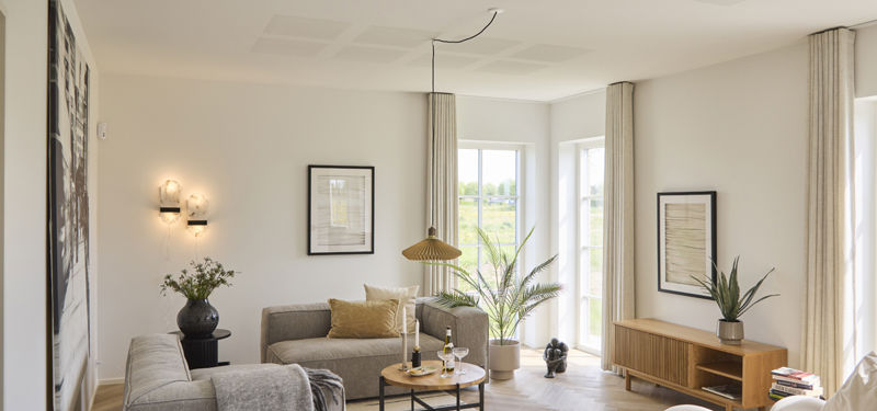 Lys stue i udstillingshus fra eurodan-huse med store vinduespartier, sofaområde, sildebensgulv og moderne indretning, der giver inspiration til nybyggeri, husbyggeri og indretning af et nyt familiehus.