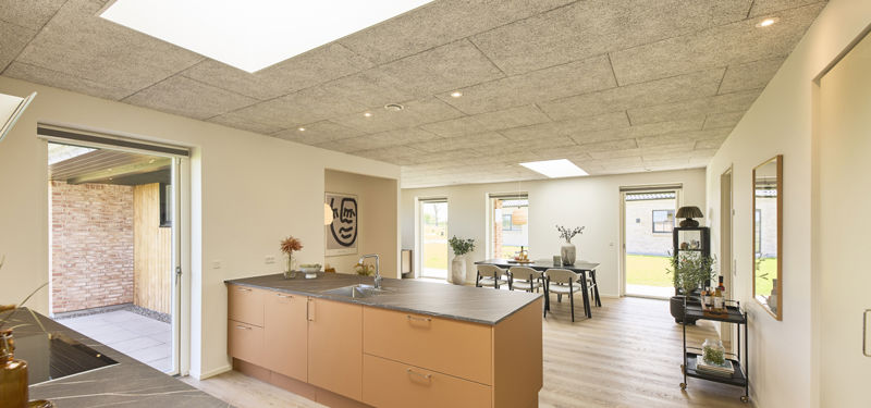 Køkken-alrum i nybygget udstillingshus fra eurodan-huse med stor køkkenø, ovenlys, akustikloft, terrasseadgang og åben forbindelse til spiseområde som inspiration til moderne husbyggeri