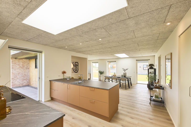 Køkken-alrum i nybygget udstillingshus fra eurodan-huse med stor køkkenø, ovenlys, akustikloft, terrasseadgang og åben forbindelse til spiseområde som inspiration til moderne husbyggeri