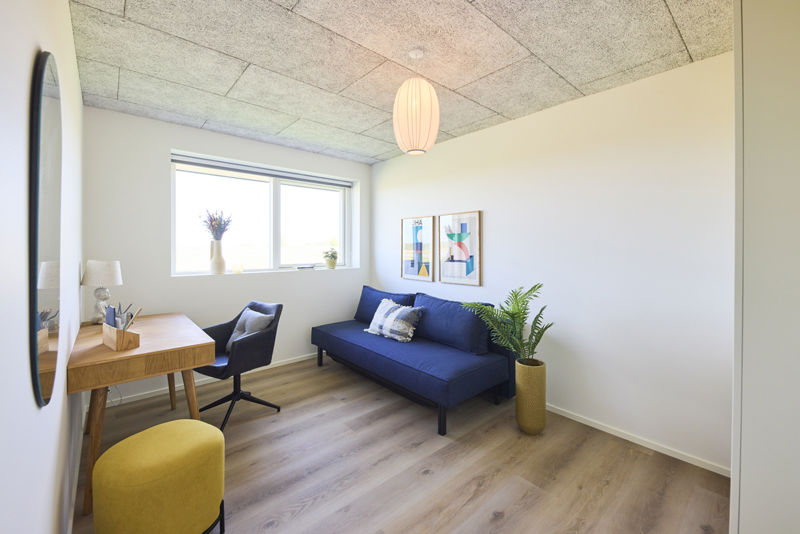 Værelse i nybygget udstillingshus fra eurodan-huse indrettet med blå daybed, skrivebord, rundt spejl og lyst trægulv som inspiration til fleksible husdrømme