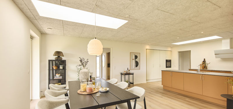 Køkken-alrum i nybygget udstillingshus fra eurodan-huse med ovenlys, sort spisebord, varme køkkenfronter og åben indretning som inspiration til moderne husbyggeri