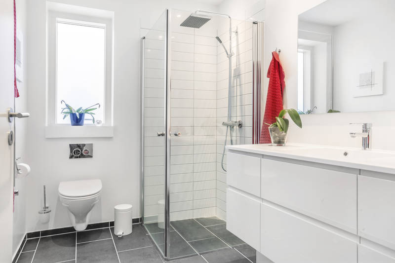 Hvidt badeværelse med lille brusekabine