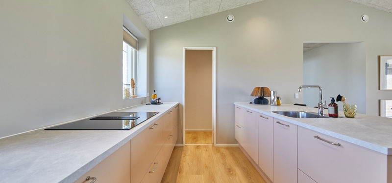 Køkken i nybygget udstillingshus fra eurodan-huse med lyse køkkenfronter, bordplade i stenlook, akustikloft, trægulv og praktisk arbejdszone som inspiration til moderne husbyggeri og husdrømme