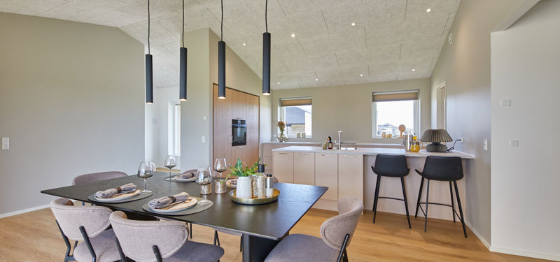 Køkken-alrum i nybygget udstillingshus fra eurodan-huse med sort spisebord, moderne pendellamper, barplads, lyse køkkenfronter og akustikloft som inspiration til husbyggeri og husdrømme