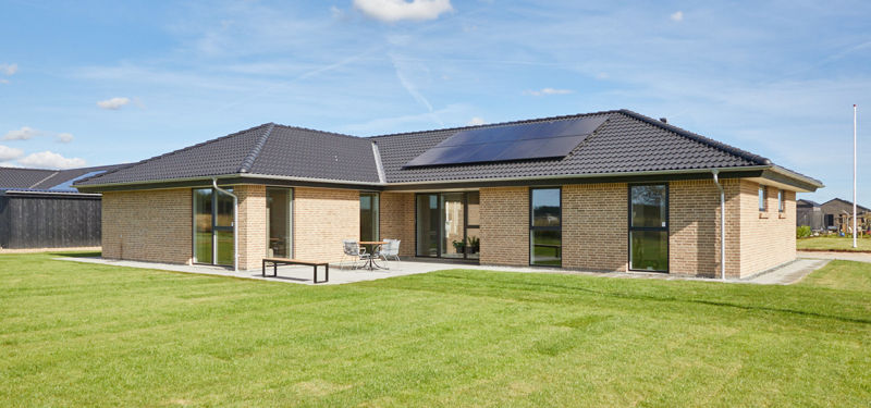 Murstenhus fra eurodan-huse med terrasse, græsplæne og solceller på taget, der viser et moderne udstillingshus til inspiration for nybyggeri og husdrømme.