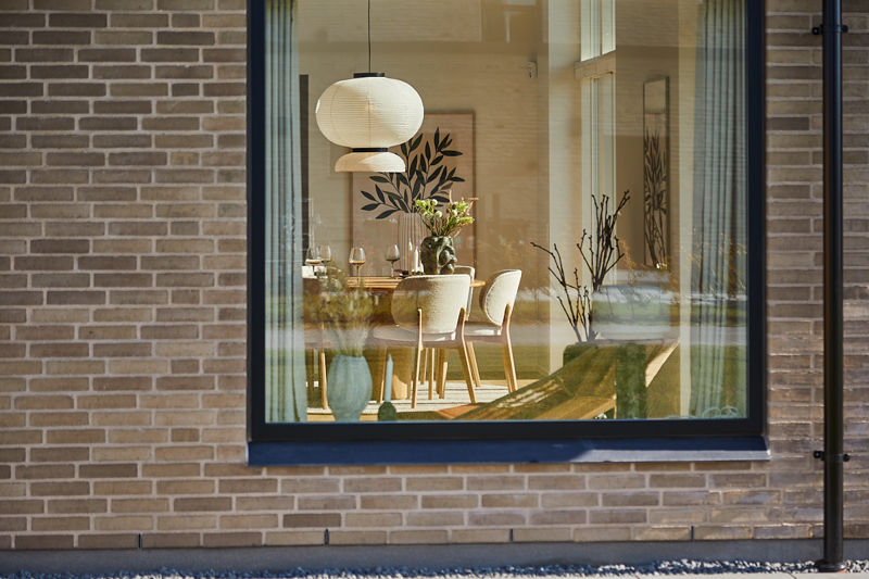 Store vinduespartier i nybyggeri med kig til spiseplads, moderne pendel og lys indretning i udstillingshus