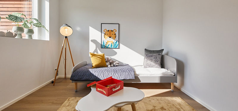 Børneværelse i nybygget familievilla med seng, legebord, varme farver og plads til familiens hverdag i moderne husbyggeri