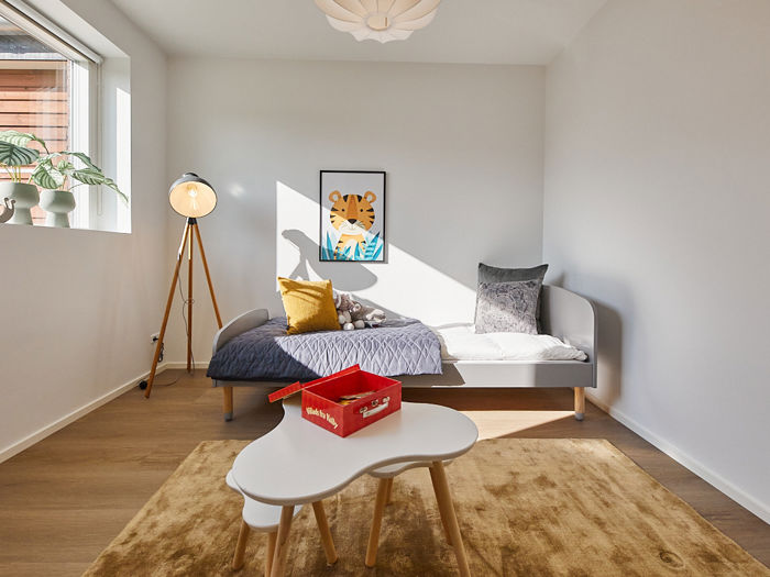Børneværelse i nybygget familievilla med seng, legebord, varme farver og plads til familiens hverdag i moderne husbyggeri