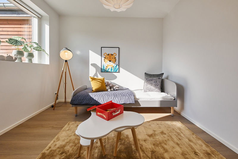 Børneværelse i nybygget familievilla med seng, legebord, varme farver og plads til familiens hverdag i moderne husbyggeri