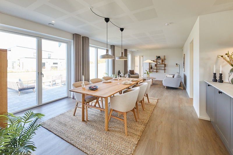 Rummeligt køkken-alrum i nybyggeri med spiseplads, gulv-til-loft vinduer, terrasseadgang og naturligt lys til moderne familieliv