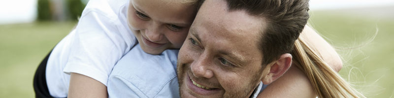 Far og datter leger og omfavner hinanden i haven ved familiens drømmehus fra eurodan-huse.