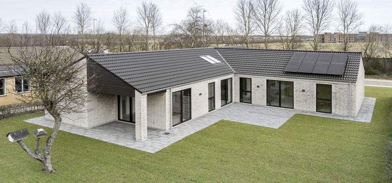 Moderne nybyggeri fra eurodan-huse med grå mursten, sort tag, solceller og flisebelagt terrasse.