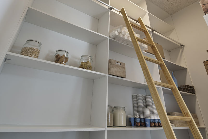 Depotrum fra eurodan-huse med høje hvide reoler, træstige på metalskinne, opbevaringsglas, dåser, service og kurve på hylderne – inspiration til organiseret opbevaring, funktionelt nybyggeri og moderne husdrømme.