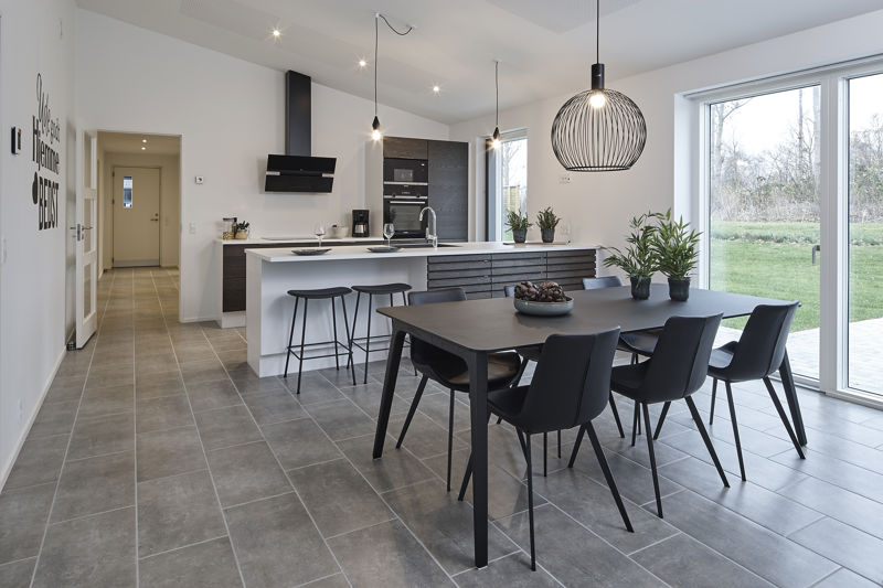 Moderne køkken fra eurodan-huse med lange lyse skabsfronter, sort armatur, arbejdsbord ved køkkenøen, indbyggede hvidevarer og åben forbindelse til spisepladsen i alrummet – konkret inspiration til funktionelt nybyggeri, køkkenopbevaring og nye husdrømme.