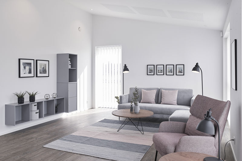 Lys stue fra eurodan-huse med grå chaiselongsofa, rosa loungestol, rundt sofabord i træ, stribet gulvtæppe, grå reol, sort væglampe og flere små billedrammer på væggen – inspiration til moderne nybyggeri, husbyggeri og indretning af en hyggelig stue.