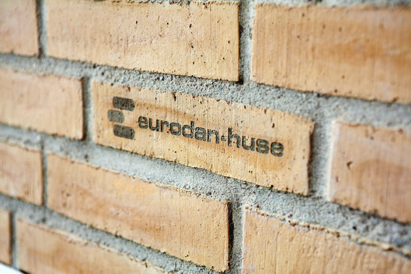 Nærbillede af eurodan-huse-logo præget i en lys mursten på facaden af et nybygget hus.