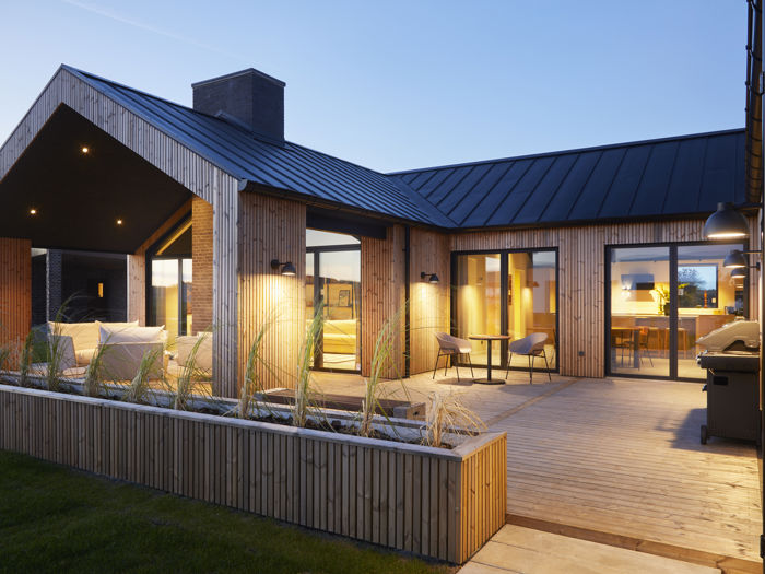 Nybygget hus med træfacade, sort tag og overdækket terrasse fra eurodan-huse