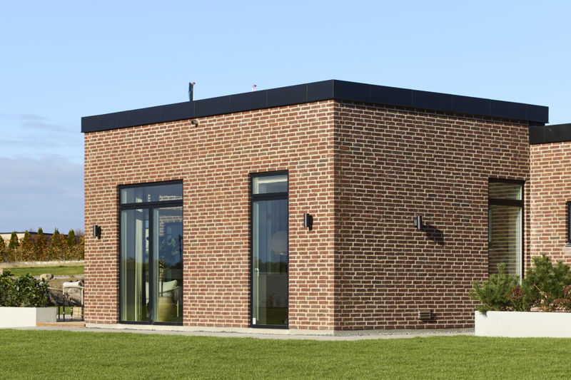 Detalje af nybygget funkishus med rødbrun teglfacade, sorte vinduesrammer og moderne arkitektur fra eurodan-huse