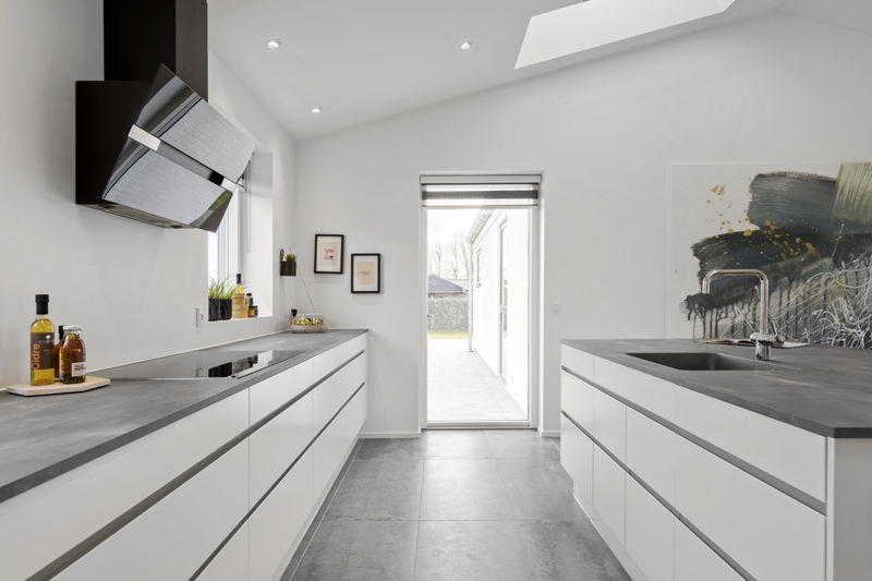 Åbent køkken-alrum fra eurodan-huse med spiseplads ved store vinduer, køkkenø med lyse fronter, mørk bordplader og gennemgående moderne indretning – inspiration til nybygget hus, funktionelt husbyggeri og husdrømme med plads til hverdagsliv.