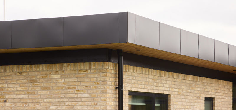 Detalje af funkisinspireret facade fra eurodan-huse med lyse mursten, sort udhæng, sort tagkant, nedløbsrør og træbeklædt underside – inspiration til moderne nybyggeri, facadevalg og arkitektoniske husdrømme.