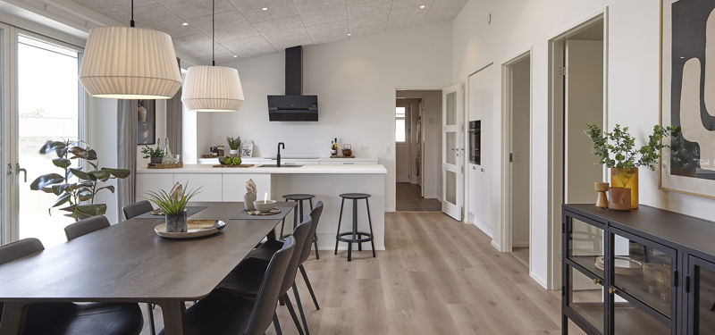 Moderne køkken fra eurodan-huse med køkkenø, barstole, integreret ovn, lyse skabsfronter, sort armatur og direkte kig til spisepladsen i alrummet – konkret inspiration til praktisk køkkenindretning, nybyggeri og husdrømme med åbne opholdsrum.