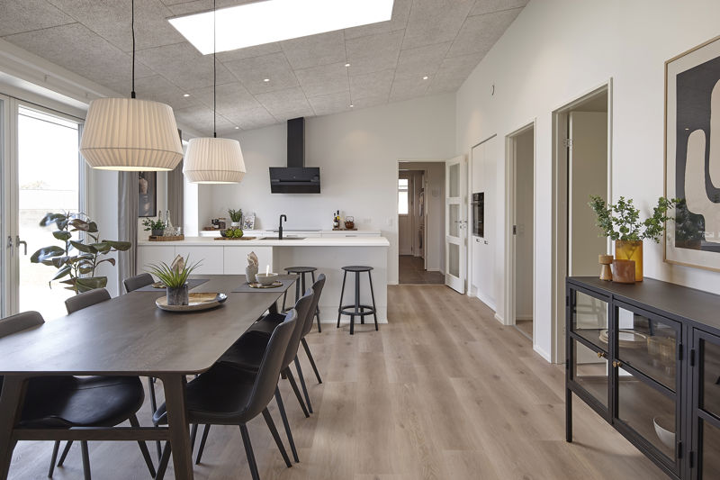 Moderne køkken fra eurodan-huse med køkkenø, barstole, integreret ovn, lyse skabsfronter, sort armatur og direkte kig til spisepladsen i alrummet – konkret inspiration til praktisk køkkenindretning, nybyggeri og husdrømme med åbne opholdsrum.