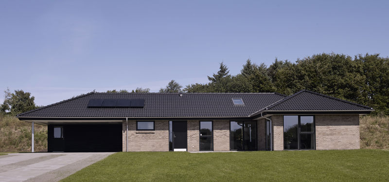 Frontfacade på vinkelhus 151 m² i lyse mursten med mørkt valmtag, solceller, integreret garage, store vinduespartier og grøn forhave – inspiration til moderne nybyggeri.