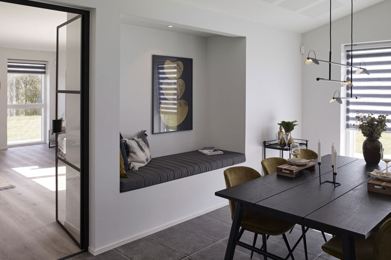 Spiseområde fra eurodan-huse med sort spisebord, sennepsfarvede stole, moderne pendel over bordet, sort rammedør og indbygget alkove med mørk hynde, puder og vægkunst – inspiration til nybyggeri og husdrømme med spiseplads og hyggekrog samlet.