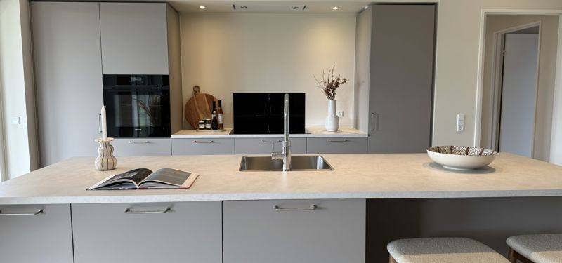 Moderne køkken i nybyggeri med stor køkkenø, barplads og stilrene grå fronter