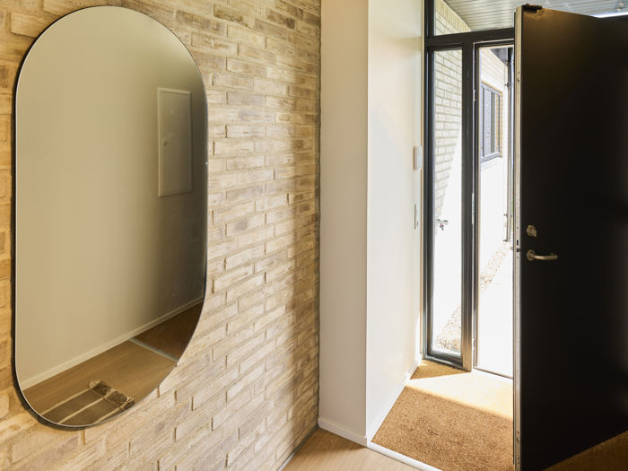 Indbydende entré med rå murstensvægge og integreret garderobe i nyt husbyggeri.