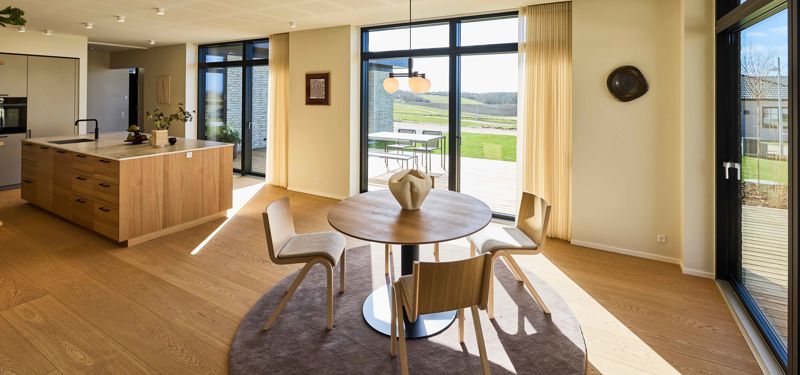 Åbent køkken-alrum med masser af dagslys – hjertet i et moderne husbyggeri i en familievilla