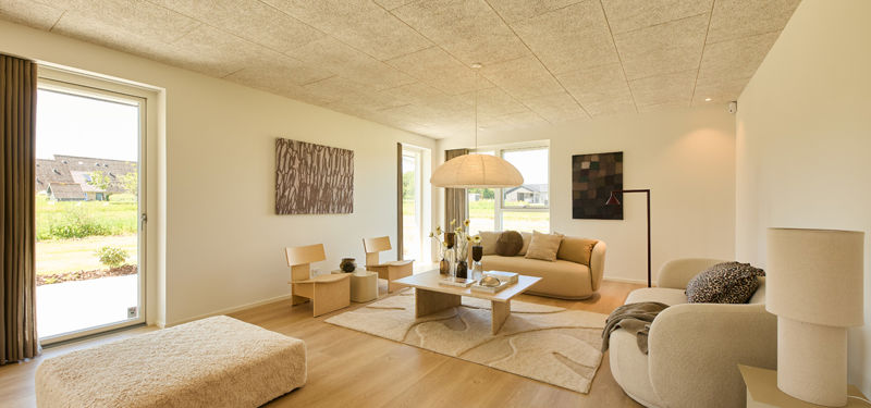 Lys stue fra eurodan-huse med beige sofa, rund loungestol, daybed, pendellampe, gulvlampe, store vinduer og lyst trægulv – inspiration til moderne nybyggeri og hyggelige husdrømme.