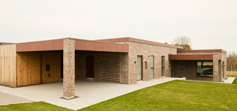 Nybygget funkishus fra eurodan-huse set fra siden med murfremspring, brune vinduesrammer og moderne facade som inspiration til husbyggeri og husdrømme