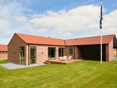 Facade fra eurodan-huse med røde mursten, rødt tegltag, sort carport, træterrasse, store glaspartier og sansevindue – inspiration til klassisk nybyggeri, terrassemiljø og husdrømme.