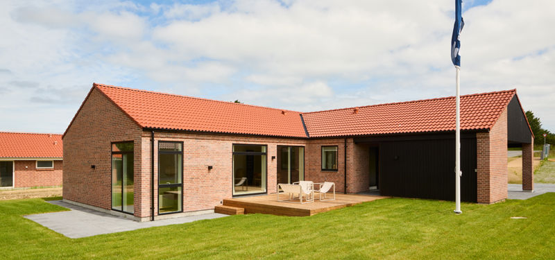 Facade fra eurodan-huse med røde mursten, rødt tegltag, sort carport, træterrasse, store glaspartier og sansevindue – inspiration til klassisk nybyggeri, terrassemiljø og husdrømme.
