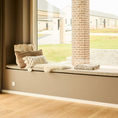 Sansevindue i nybygget udstillingshus fra eurodan-huse med indbygget siddeplads, udsigt til haven og hyggelig detalje til husdrømme