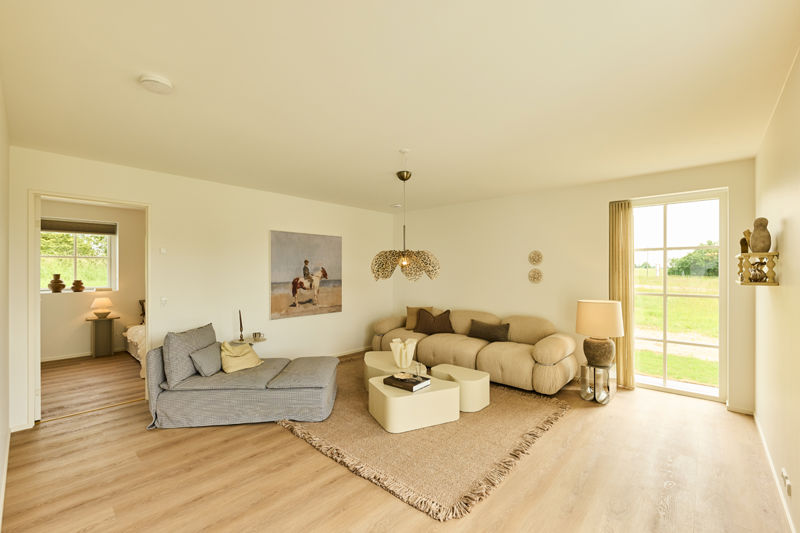 Hyggelig stue fra eurodan-huse med beige sofa, chaiselong, lyse sofaborde, gulvtæppe, pendellampe, stor terrassedør med sprosser og kig til værelse – inspiration til nybyggeri.