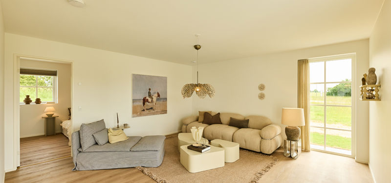 Hyggelig stue fra eurodan-huse med beige sofa, chaiselong, lyse sofaborde, gulvtæppe, pendellampe, stor terrassedør med sprosser og kig til værelse – inspiration til nybyggeri.